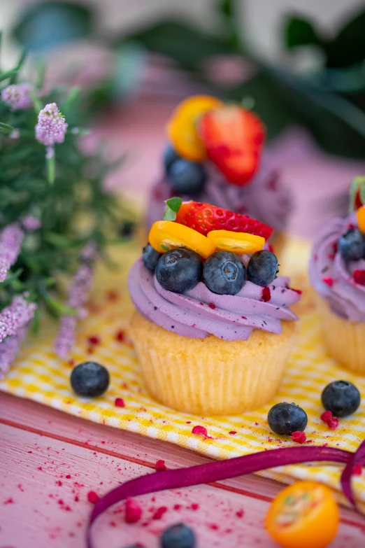 a couple of cupcakes sitting on top of a table, a picture, some red and purple and yellow, blueberries on the side, 👅 👅, profile image