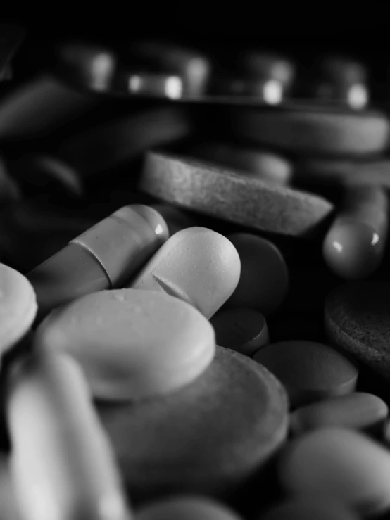 a bunch of pills sitting on top of a table, a black and white photo, by Kristian Kreković, cinematic. by leng jun, paul barson, enhanced