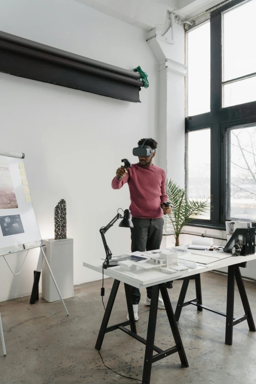 a man standing next to a table in a room, a computer rendering, trending on unsplash, arbeitsrat für kunst, wearing vr goggles, architect studio, a teen black cyborg, opening shot