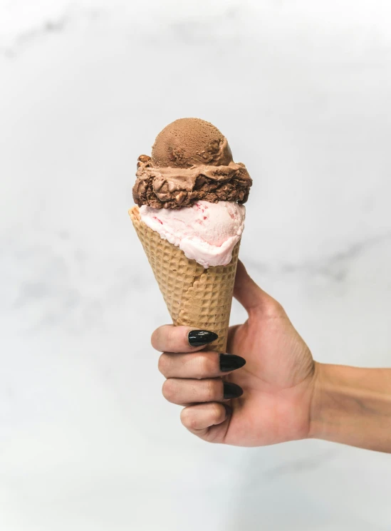 a person holding an ice cream cone in their hand, pink concrete, fully chocolate, full product shot, displayed