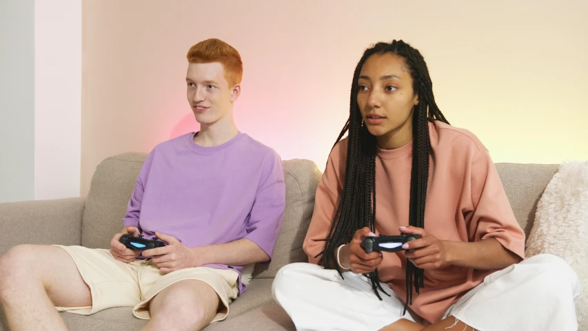 two people sitting on a couch playing video games, pexels, realism, mauve and cyan, mix of ethnicities and genders, on a pale background, uk