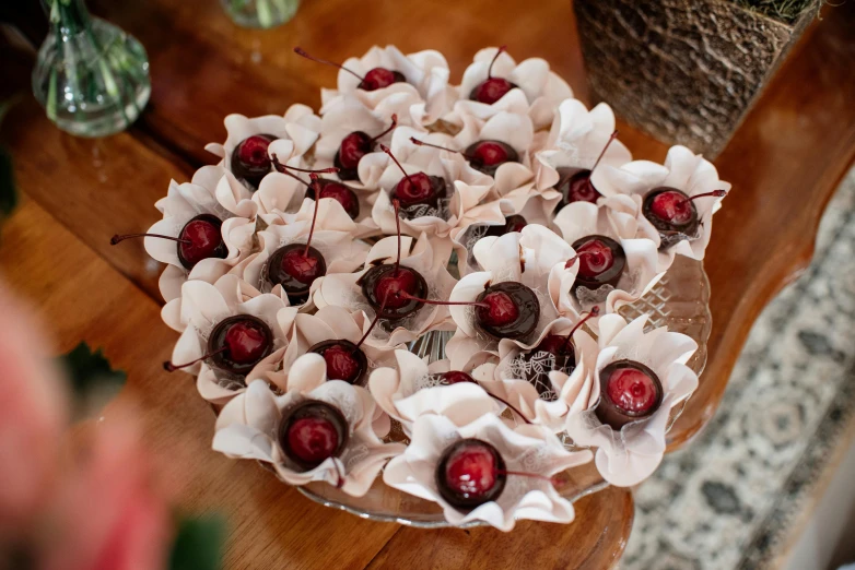 a close up of a plate of cherries on a table, magnolia goliath head ornaments, fully chocolate, thumbnail, flannel flower