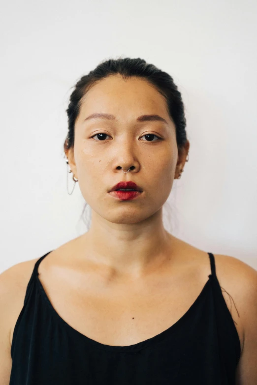 a woman standing in front of a white wall, inspired by Kim Tschang Yeul, unsplash, hyperrealism, red lipstick on face, serious and stern expression, south east asian with round face, halfbody headshot