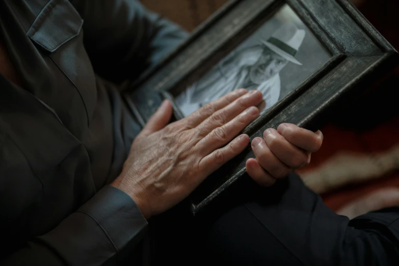 a close up of a person holding a picture, frail, sleek hands, still photograph
