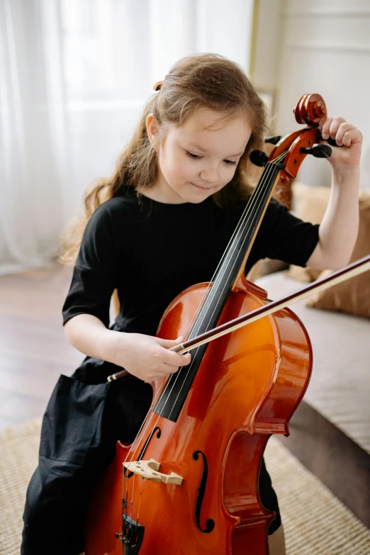 a young girl playing a cello in a living room, by Elizabeth Durack, pexels contest winner, holding a bow, promo image, profile pic, thumbnail
