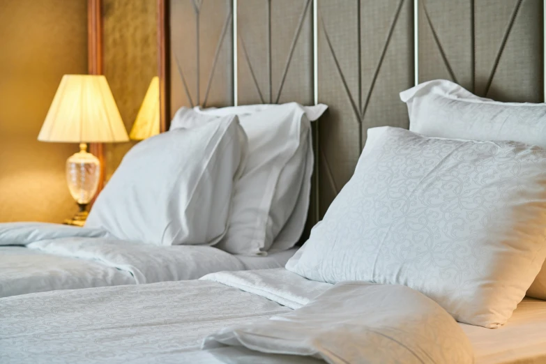 a couple of white pillows sitting on top of a bed, inspired by Henri Le Sidaner, unsplash, art nouveau, hotel, brown, grey, angled