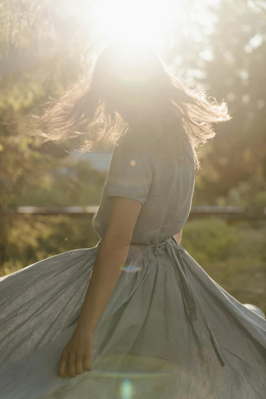 a woman standing on top of a lush green field, unsplash, renaissance, ethereal glare of the sun, wearing silver dress, whirling, walking away