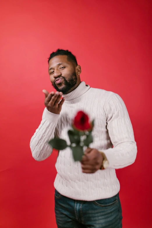 a man with a rose in his hand on a red background, trending on pexels, jemal shabazz, making out, in front of white back drop, samson pollen