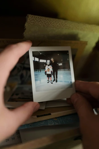 a person holding a polaroid on top of a shelf, with a kid, movie still frame, high angle close up shot, center of image