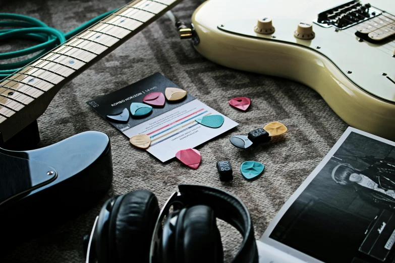 a guitar sitting on top of a carpet next to headphones, pexels contest winner, synthetism, pair of keycards on table, coloured, payne's grey and venetian red, gem tones