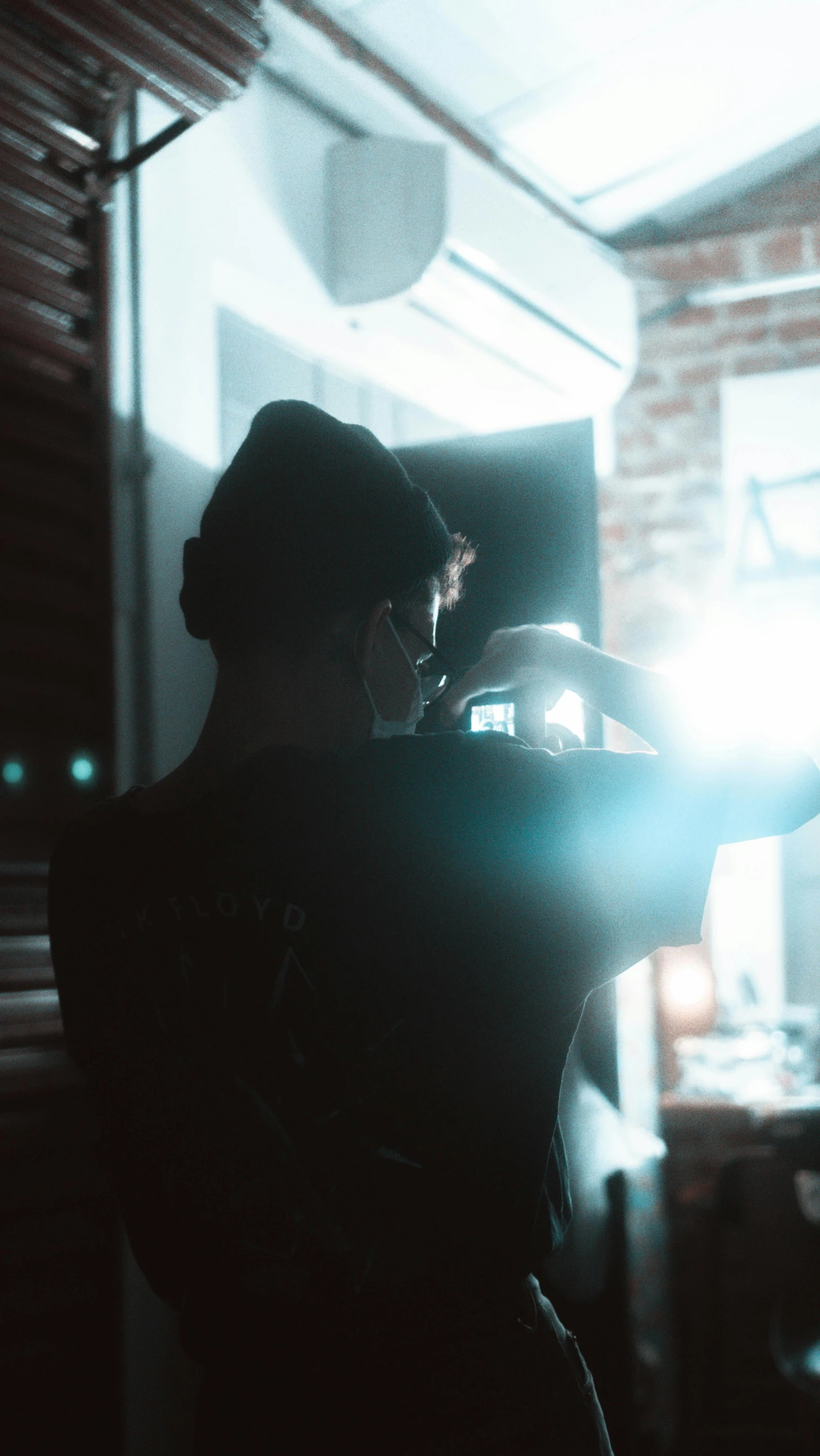 a person taking a picture with a camera, inspired by Elsa Bleda, pexels, light and space, dim flashlight lighting, back facing the camera, ;cinematic lighting, medium format