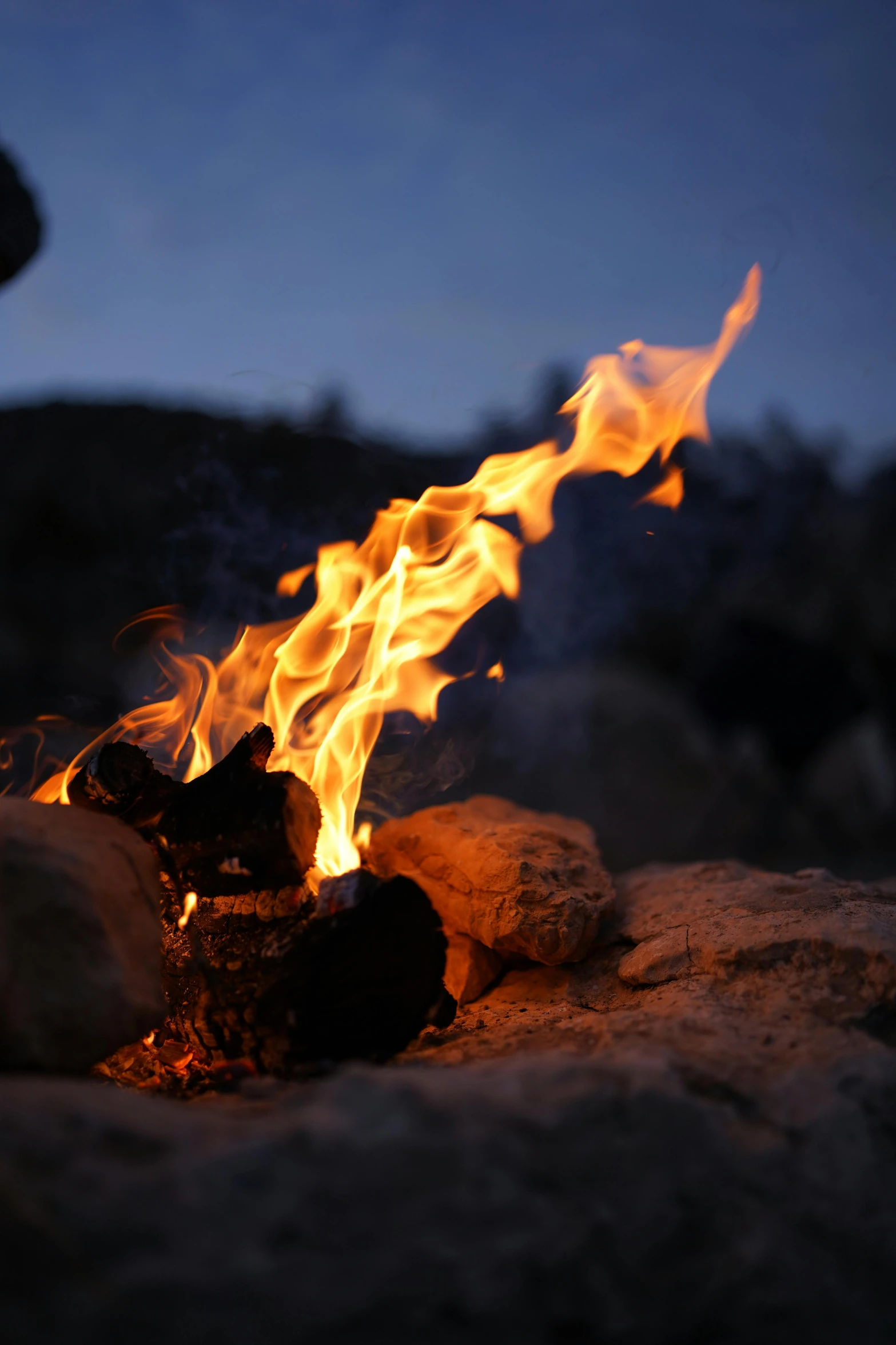 a person sitting on top of a rock next to a fire, up close, fire above head, closeup, avatar image