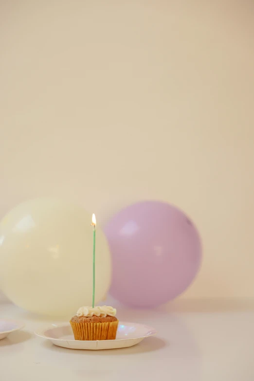 a cupcake with a candle sitting on a plate, by Alison Geissler, postminimalism, party balloons, medium format. soft light, ignant, 15081959 21121991 01012000 4k