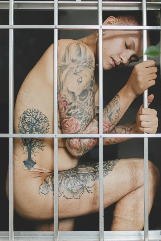 a man with tattoos sitting in a jail cell, a tattoo, inspired by Seb McKinnon, trending on pexels, conceptual art, non binary model, nature outside, transparent body, 18 years old