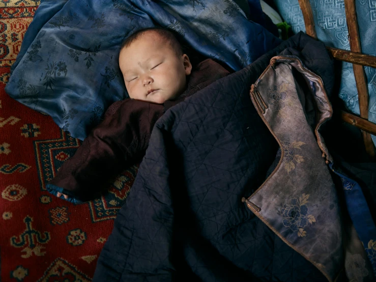 a baby sleeping on top of a blue blanket, unsplash contest winner, cloisonnism, portrait of an adventurer, fabrics and textiles, shot on hasselblad, bo xun ling