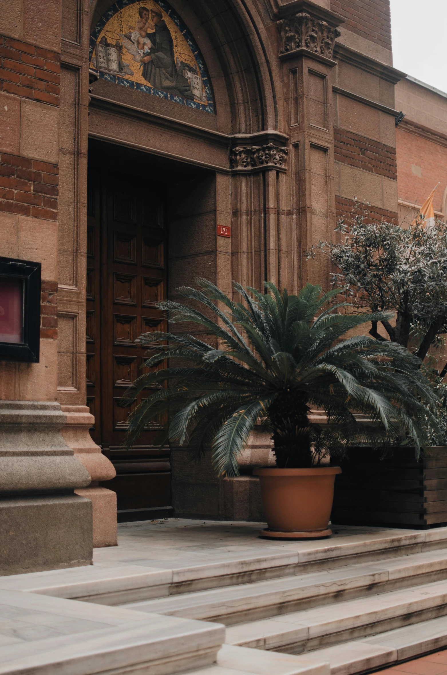 a red fire hydrant sitting in front of a building, inspired by Tomàs Barceló, pexels contest winner, art nouveau, with interior potted palm trees, copper details, television show, doorway