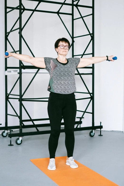 a woman standing on a yoga mat holding two dumbbells, a picture, by Rachel Reckitt, motion capture system, arms stretched out, rebecca sugar, studio bones