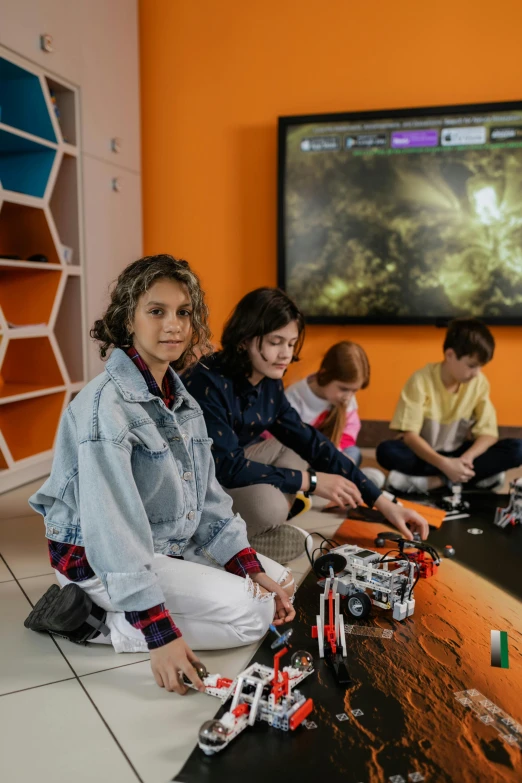 a group of people sitting on the floor playing a video game, pexels contest winner, danube school, bionicle, space craft, mini model, - 9