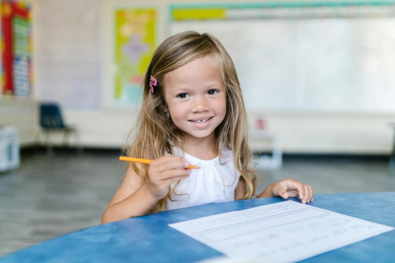 a little girl sitting at a table with a pencil in her hand, pexels contest winner, danube school, a confident smile, 15081959 21121991 01012000 4k, lachlan bailey, portrait of small