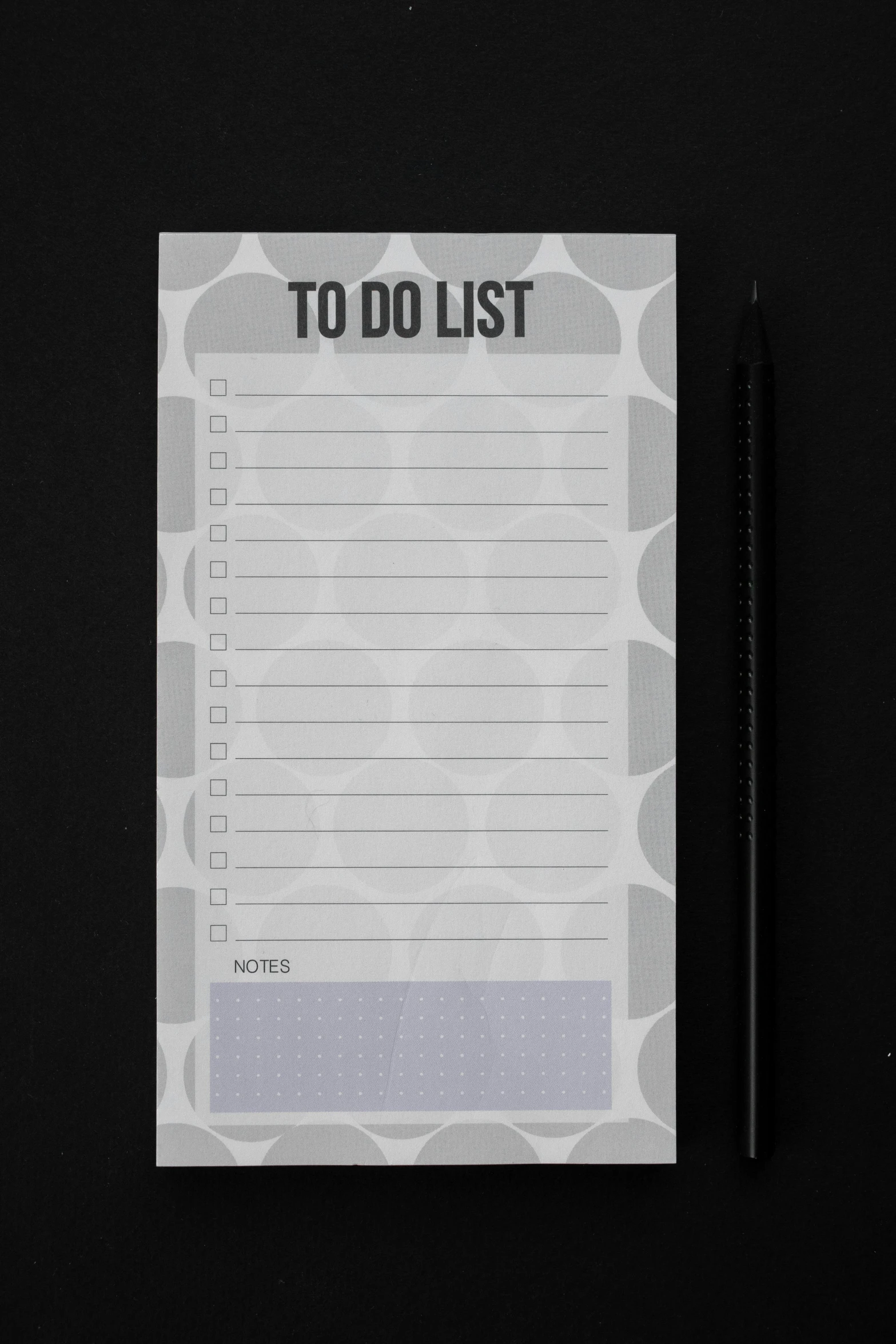 a notepad sitting on top of a table next to a pen, grey and dark theme, black dots, 0, list