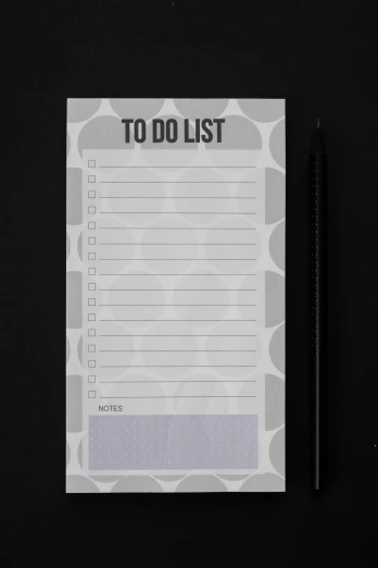 a notepad sitting on top of a table next to a pen, grey and dark theme, black dots, 0, list