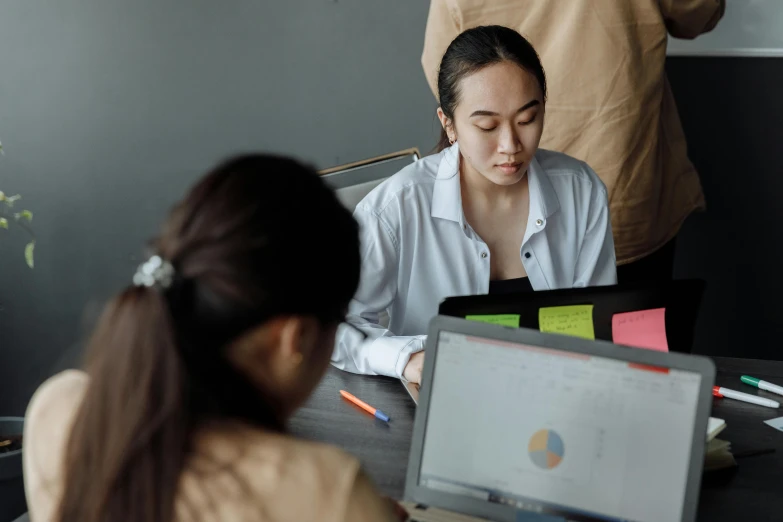 a group of people sitting around a table with laptops, trending on pexels, analytical art, an asian woman, background image, grey, woman with braided brown hair
