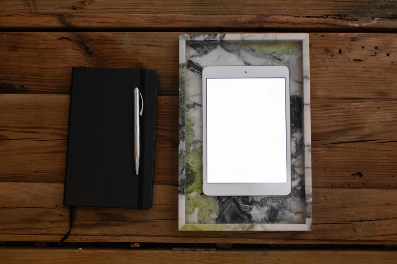 a tablet computer sitting on top of a wooden table, inspired by Brice Marden, arbeitsrat für kunst, marble and wood and glass, holding notebook, light frame, handcrafted