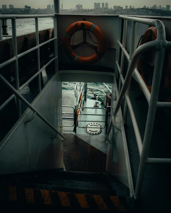 a boat on a body of water with a city in the background, an album cover, by Elsa Bleda, pexels contest winner, stairs to the second floor, ship interior, wet floor, depressing image