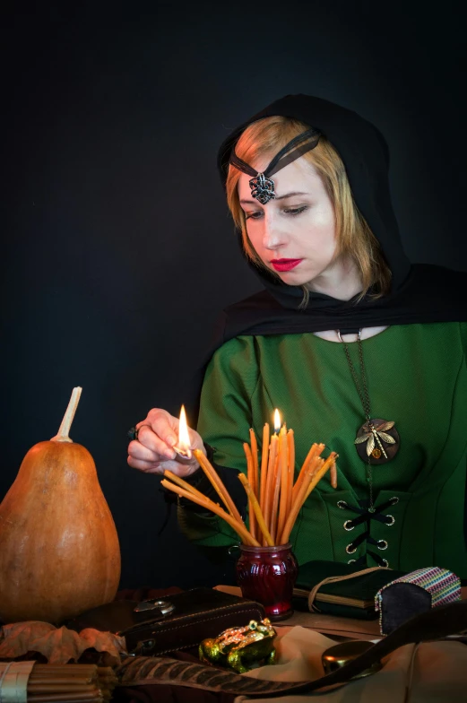 a woman sitting at a table with a candle in her hand, inspired by Michelangelo Merisi da Caravaggio, renaissance, dressed as a wizard, trick or treat, press shot, cosplay photo