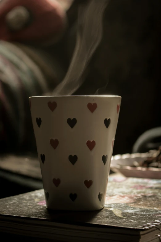 a coffee cup sitting on top of a stack of books, a picture, by Elsa Bleda, trending on pexels, romanticism, hearts, moroccan tea set, steamy, patterned