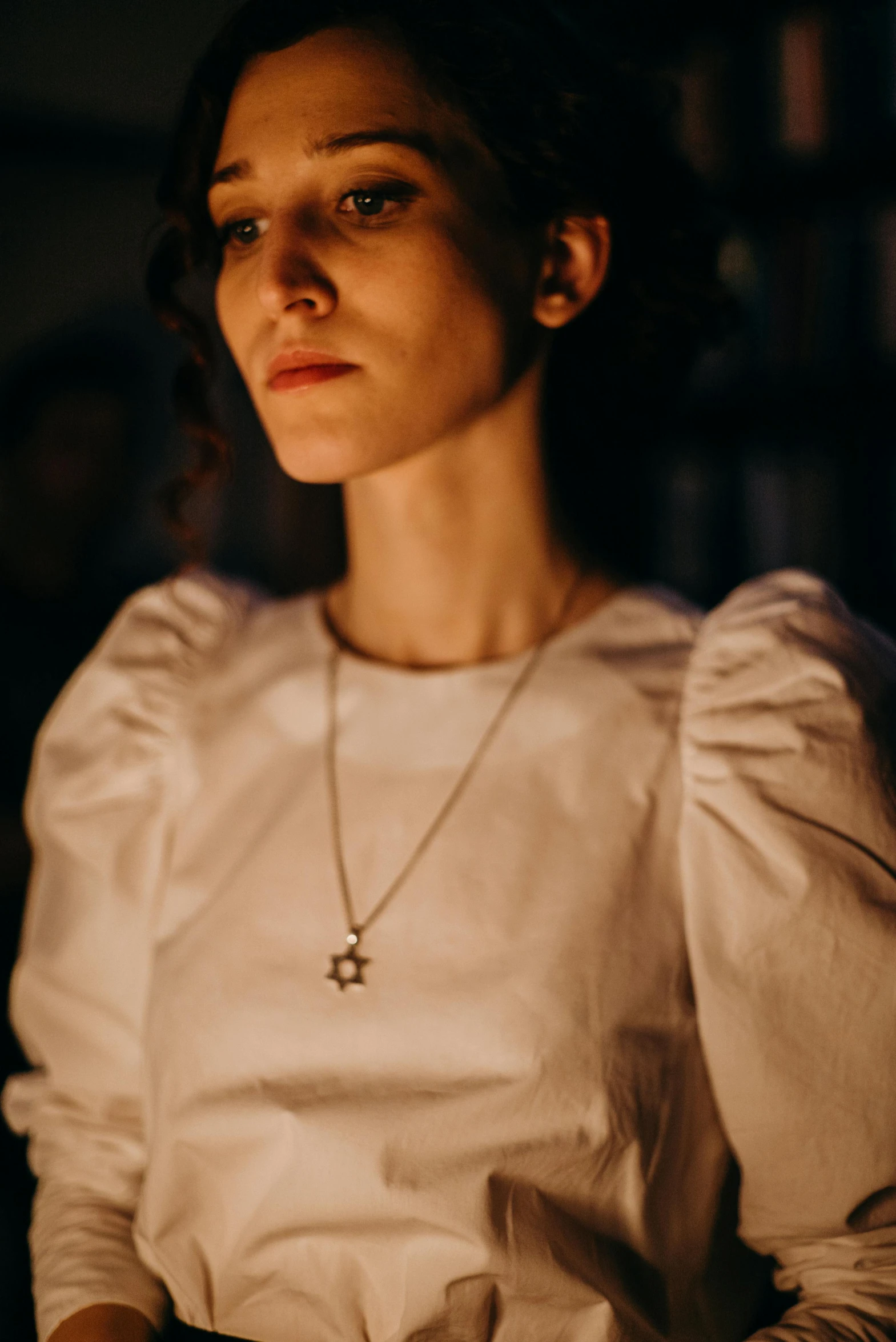 a woman holding a lit candle in a dark room, inspired by Elsa Bleda, renaissance, silver necklace, wearing a white blouse, with stars, puff sleeves