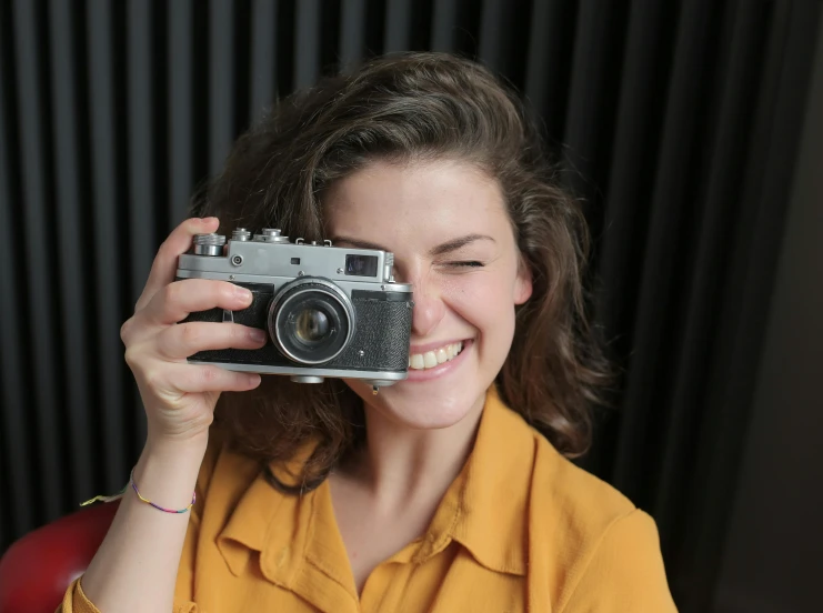 a woman taking a picture with a camera, pexels contest winner, photorealism, winking at the camera, aged 2 5, medium format, smiling