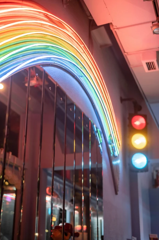 a rainbow painted on the side of a building, a hologram, by Bernie D’Andrea, kinetic art, in a classic 5 0 s diner, interior lighting, nacreous lights, looking this way