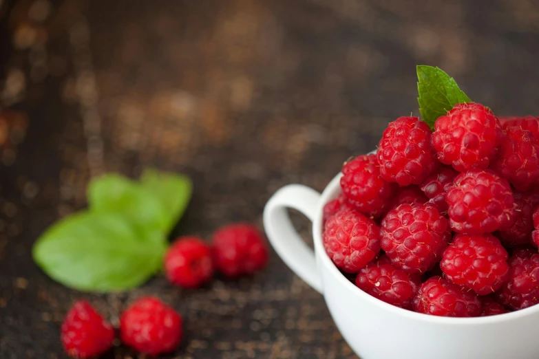 a white cup filled with raspberries on top of a wooden table, vibrantly lush, high quality product image”, fan favorite, dessert