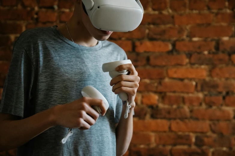 a man standing in front of a brick wall holding a nintendo wii controller, an ambient occlusion render, pexels contest winner, interactive art, vr helmet on man, oculus quest 2, drink, thumbnail