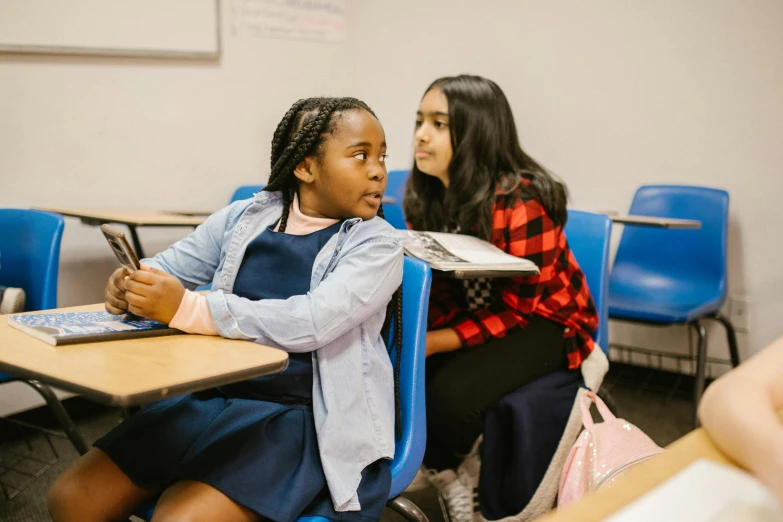 a group of girls sitting at desks in a classroom, by Carey Morris, pexels contest winner, medium shot of two characters, calmly conversing 8k, riyahd cassiem, confident looking