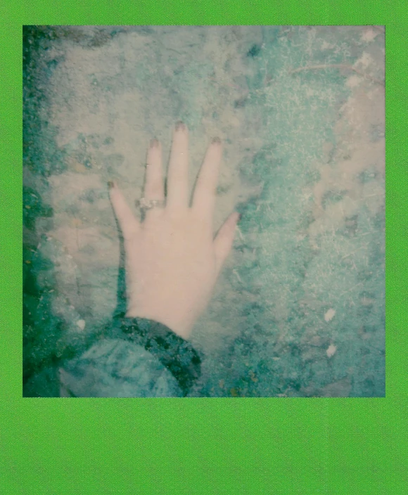 a close up of a person's hand on a snow covered ground, a polaroid photo, inspired by Elsa Bleda, trending on pexels, post-impressionism, green neon, green stained glass, album cover, holographic plastic