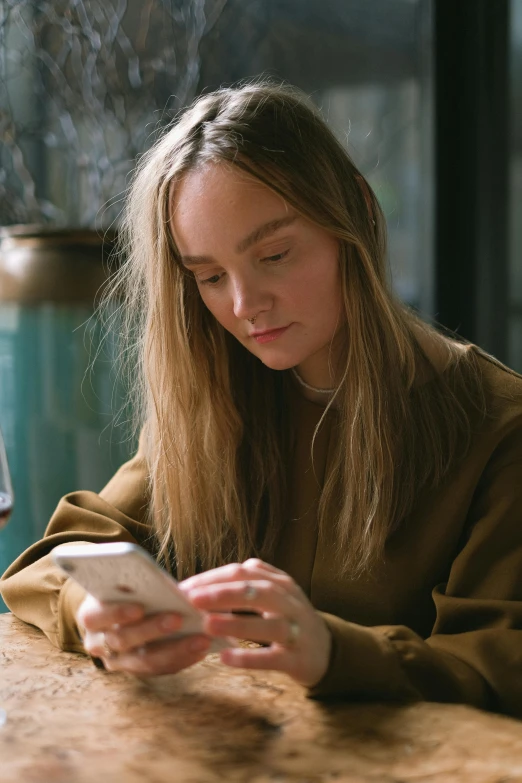 a woman sitting at a table looking at her cell phone, a portrait, trending on pexels, renaissance, sydney sweeney, girl with brown hair, student, textured