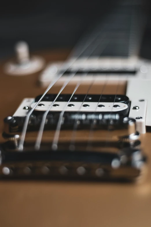 an electric guitar sitting on top of a wooden table, zoomed in, on a gray background, intricate detailing, zoomed out