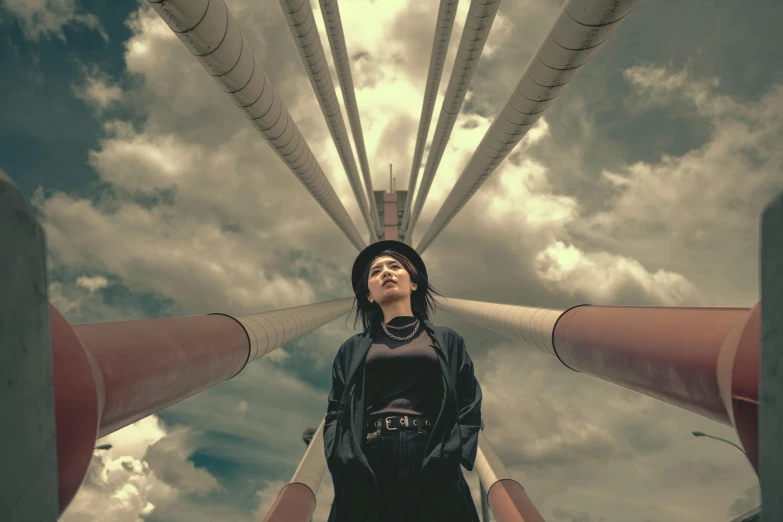 a woman standing in front of a bunch of pipes, inspired by Alexander Rodchenko, pexels contest winner, sky bridge, clouds around, young woman looking up, high quality photo