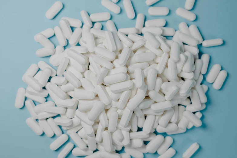 a pile of white pills on a blue background, by Elsa Bleda, unsplash, plasticien, white sleeves, ultra detailed, orelsan, on grey background