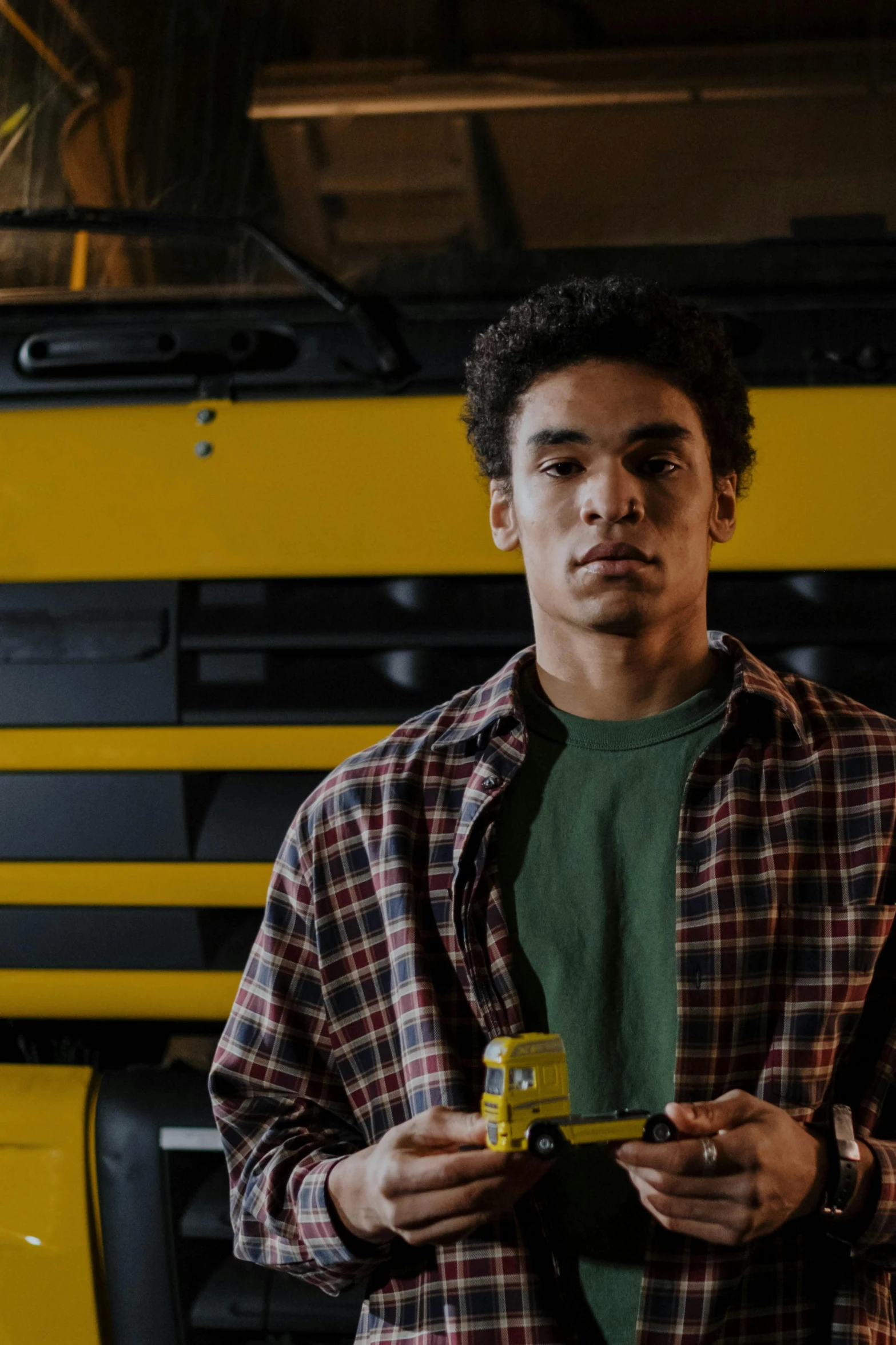 a man standing in front of a yellow school bus, pexels, hyperrealism, holding a bottle of beer, in a warehouse, a black man with long curly hair, worksafe. cinematic