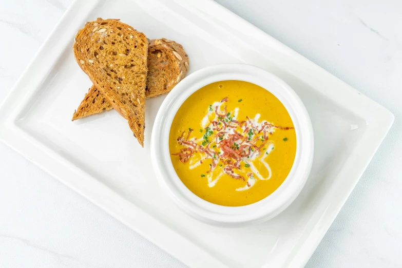 a white plate topped with a bowl of soup next to a slice of bread, ochre, detailed product image, white sky, square