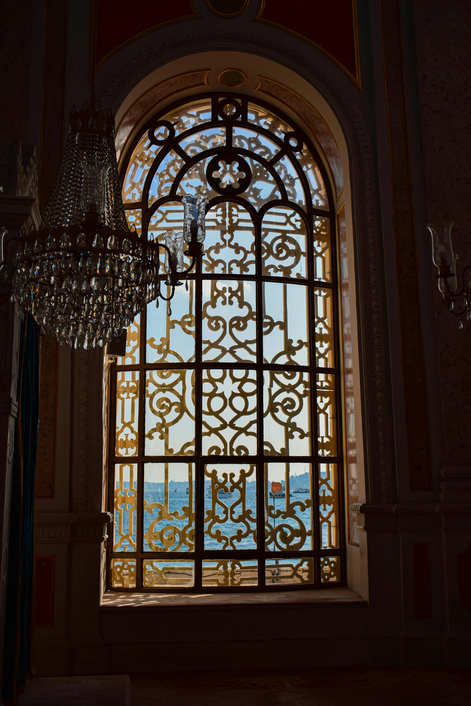 a chandelier in front of a window with a view of the ocean, inspired by Albert Dorne, unsplash, rococo, istanbul, inlaid with gold, royal palace interior, wrought iron