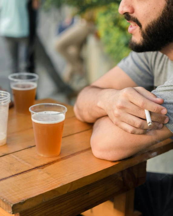 a man sitting at a table with a cigarette in his hand, a cartoon, trending on unsplash, beer, lgbt, mid shot photo, multiple stories