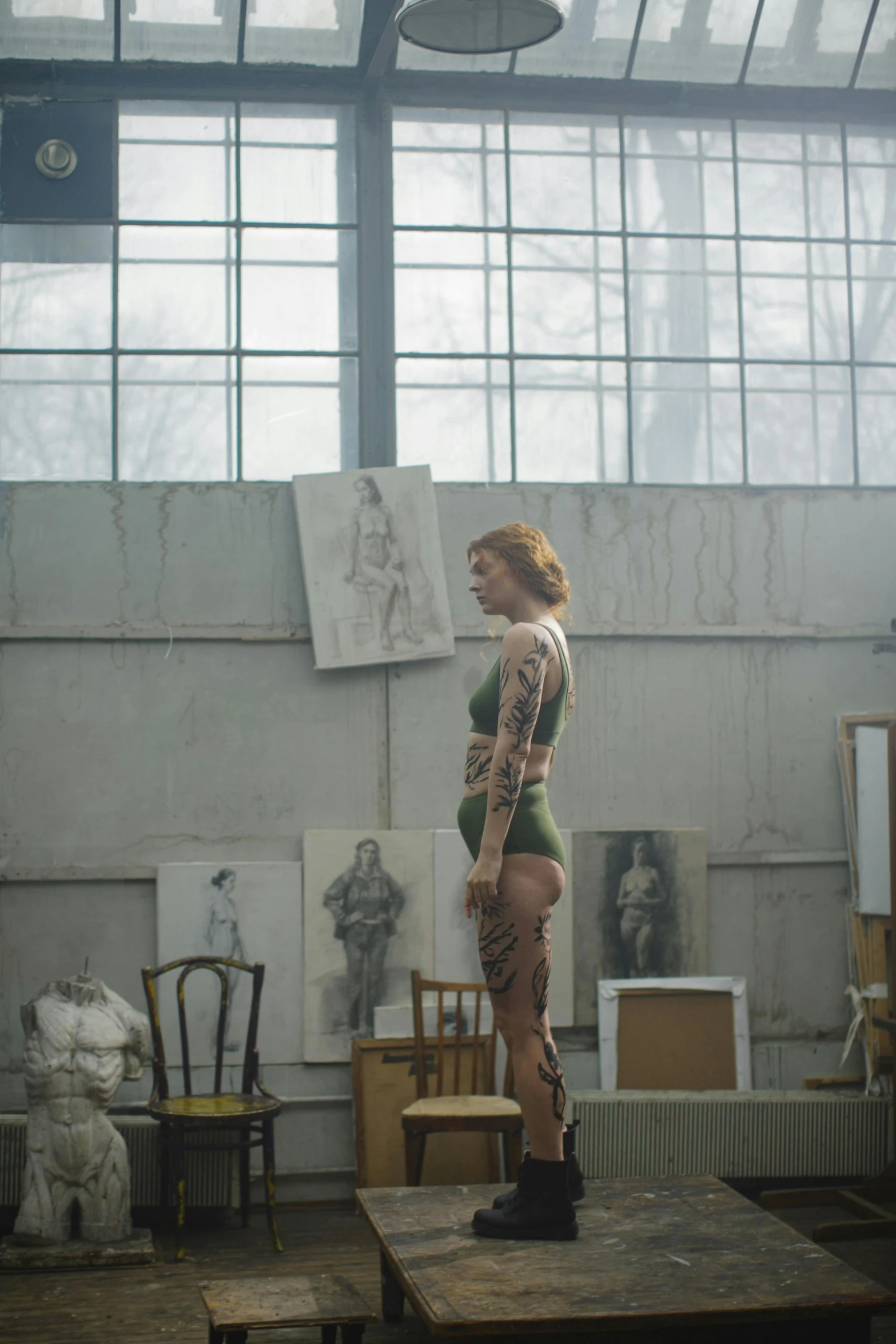 a woman standing on top of a wooden table, a tattoo, inspired by Elizabeth Polunin, in a museum room, cinematic still, sophia lillis, costume design