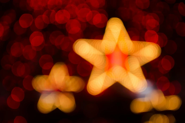 a close up of a star with blurry lights in the background, an album cover, pexels, symbolism, red and yellow light, holiday season, bokeh. i, profile image