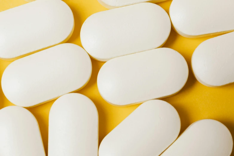 a bunch of white pills sitting on top of a yellow surface, by Chris Rahn, unsplash, white panels, incubator medpods, vanilla, shields