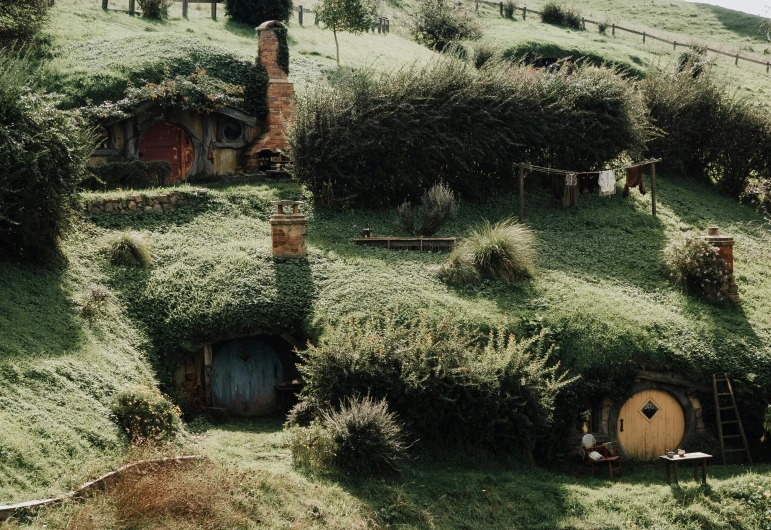 a group of people standing on top of a lush green hillside, by Carey Morris, unsplash contest winner, hurufiyya, in his hobbit home, buildings, gimli from lord of the rings, holes
