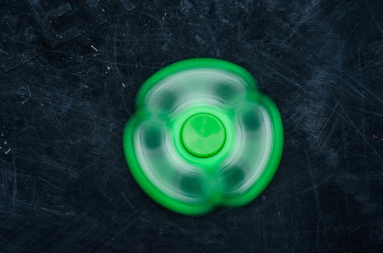 a green frisbee sitting on top of a black surface, inspired by Otto Piene, unsplash, graffiti, it has six thrusters in the back, clover, translucent, spinning whirlwind